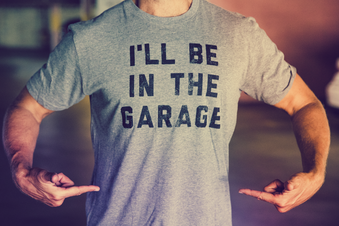Guy pointing to his grey I'll be in the garage printed shirt